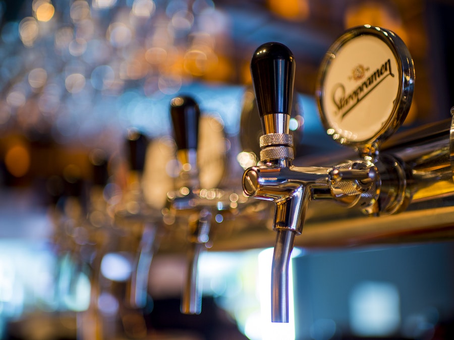 A nondescript chrome plated beer tap at a bar with more beer taps blurred in the background