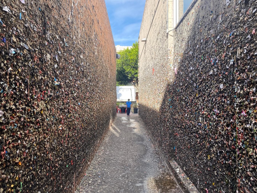 A narrow alley with its walls lined with thousands of new and old wads of chewed bubblegum stuck to it