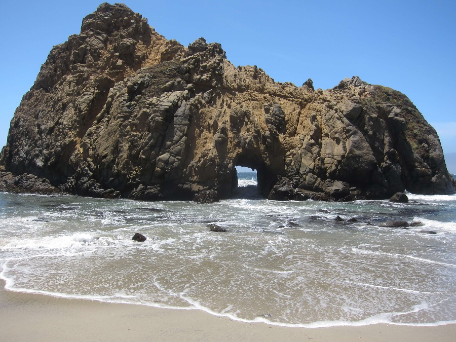 Keyhole Arch rock formation on the shore with small tunnel displaying the pacific ocean at Pfeiffer beach in Big Sur