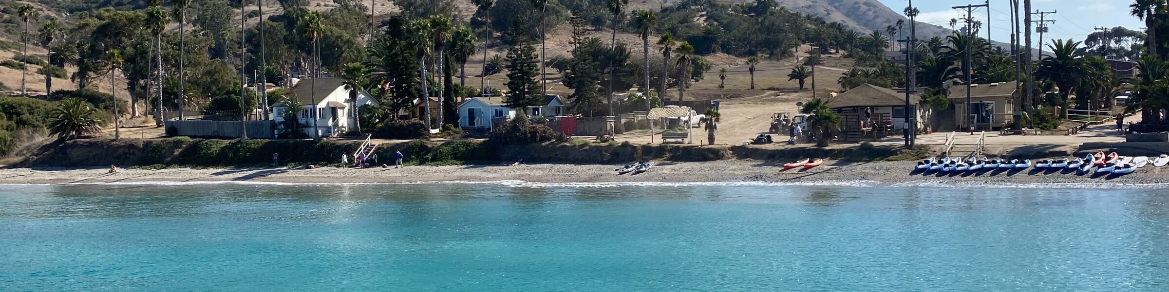 Light blue ocean water in front of a sandy beach with kayaks on Catalina Island in Los Angeles California