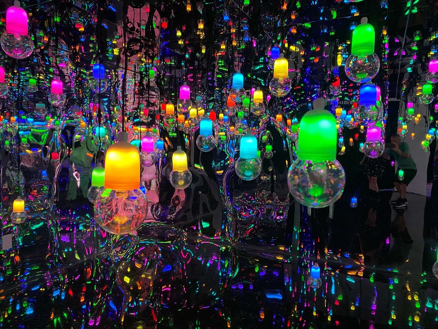 Bright multicolor hanging plasma balls in a dark room with mirrors giving a psychedelic effect.