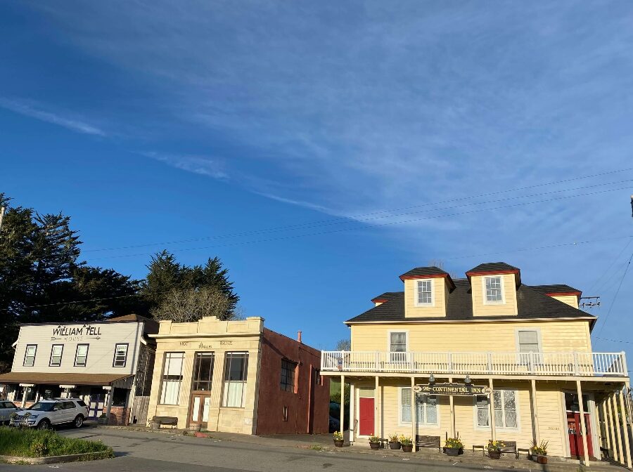 Three historic yellow hotel buildings with trees and blue sky in Tomales California. Link to Where to Stay on page.