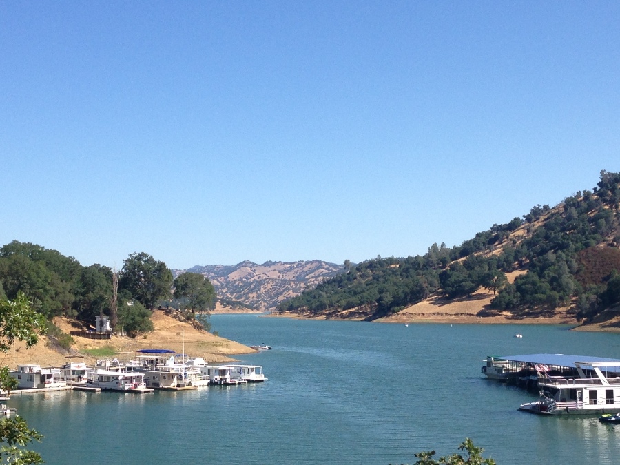 Houseboats docked on Lake Berryessa surrounded by beige hills and green trees. Link to Napa Valley page.