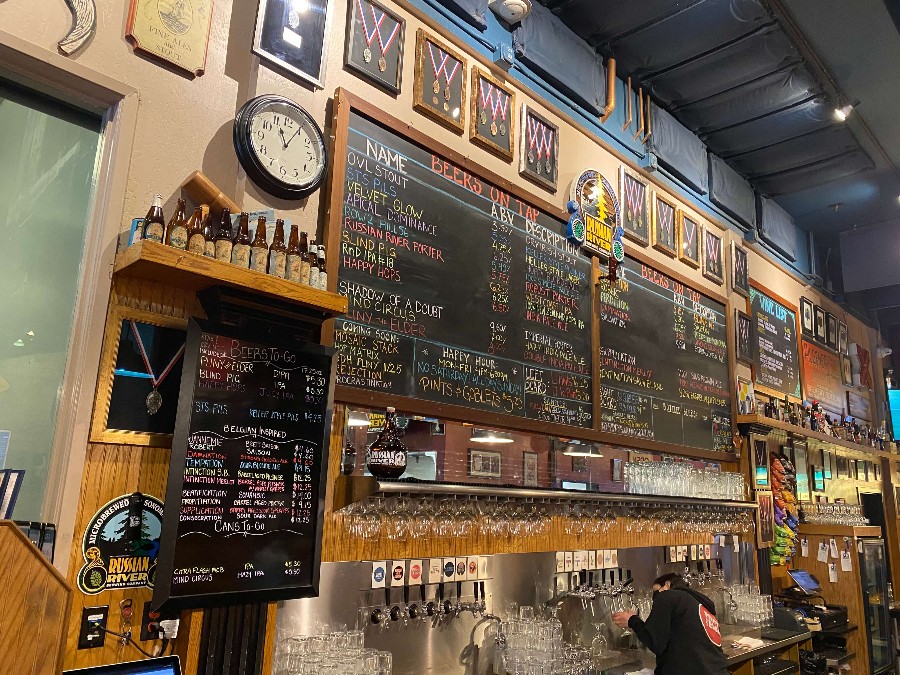 Wall with chalkboard of a beer menu and award medallions in Russian River Brewery. Link to Where to Find a Drink on page