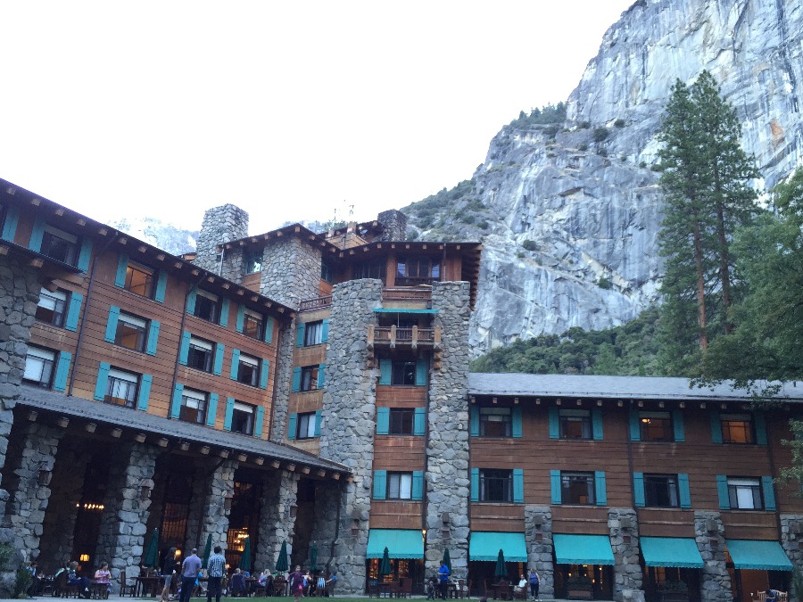 Backside courtyard of the Ahwahnee hotel and lounge tables with granite cliffs and trees in the background