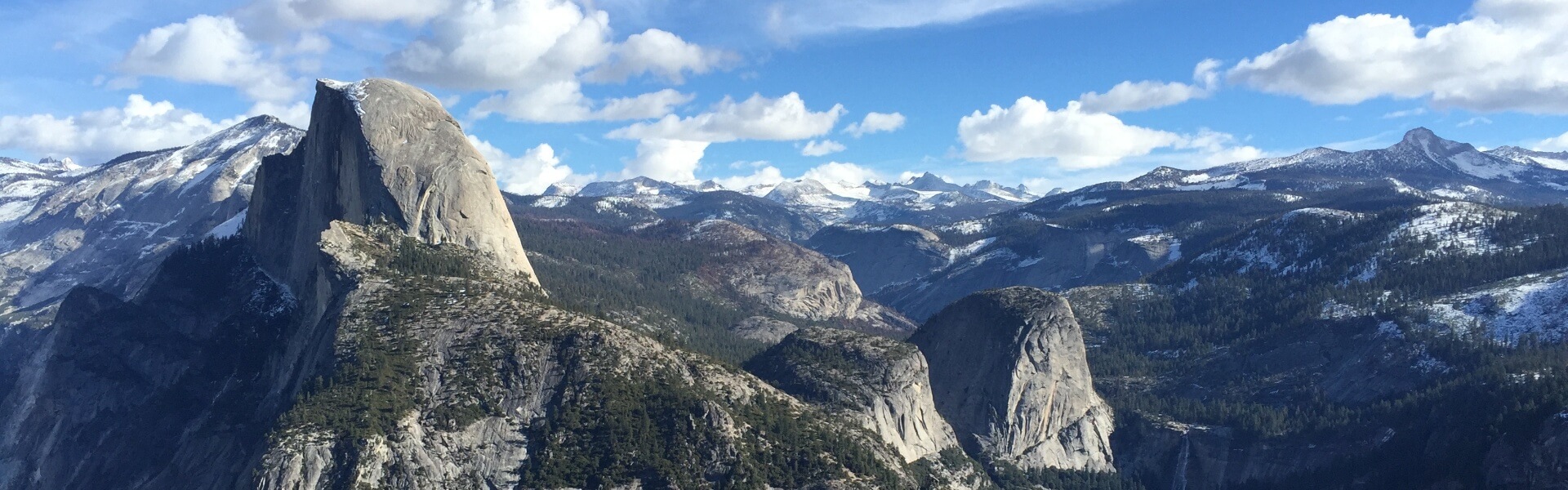 High elevation view of Half Dome and snow capped mountains from Glacier Point in Yosemite