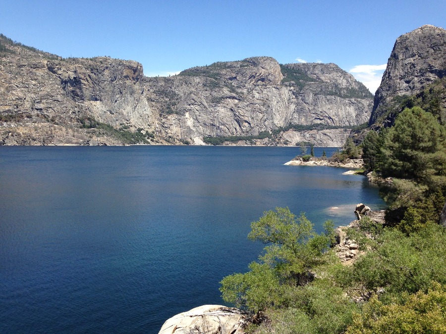 Hetch Hetchy water reservoir surrounded by green trees and rocky cliffs in Yosemite National Park.